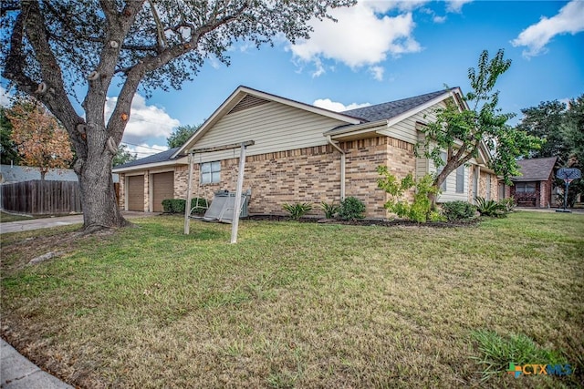 view of side of property featuring a lawn, driveway, fence, a garage, and brick siding