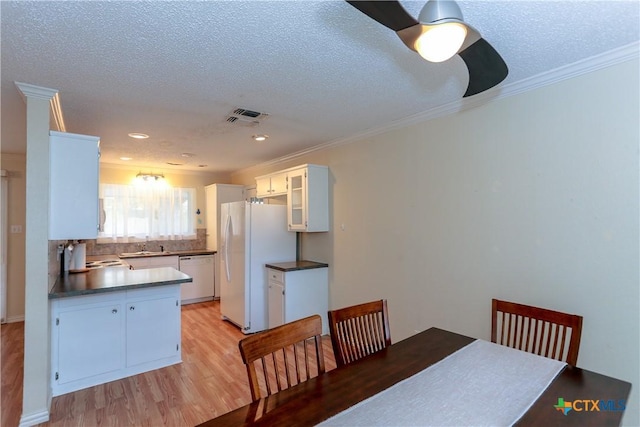 dining area featuring ceiling fan, light wood-type flooring, ornamental molding, and a textured ceiling