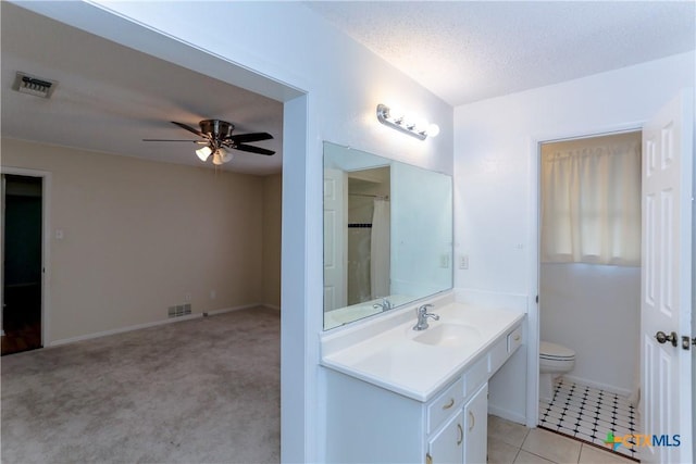 bathroom featuring a textured ceiling, tile patterned flooring, vanity, toilet, and ceiling fan