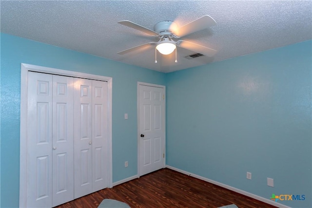 unfurnished bedroom featuring dark wood-type flooring, ceiling fan, and a textured ceiling