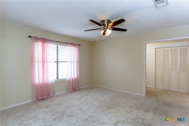 unfurnished bedroom featuring ceiling fan, light colored carpet, and a closet