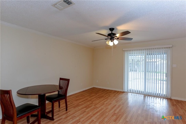 dining space featuring ceiling fan, light hardwood / wood-style floors, a textured ceiling, and crown molding