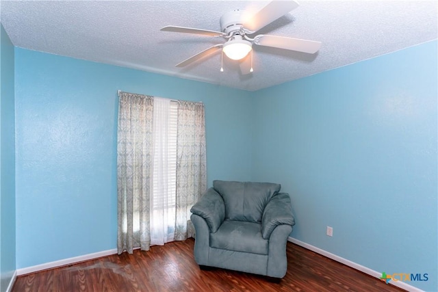 sitting room featuring ceiling fan, dark wood-type flooring, and a textured ceiling