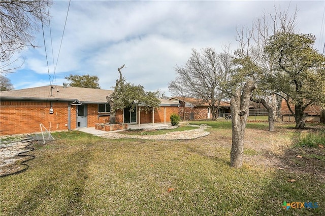 rear view of property featuring a lawn and a patio