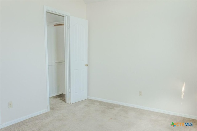 unfurnished bedroom featuring a walk in closet, light carpet, and a closet