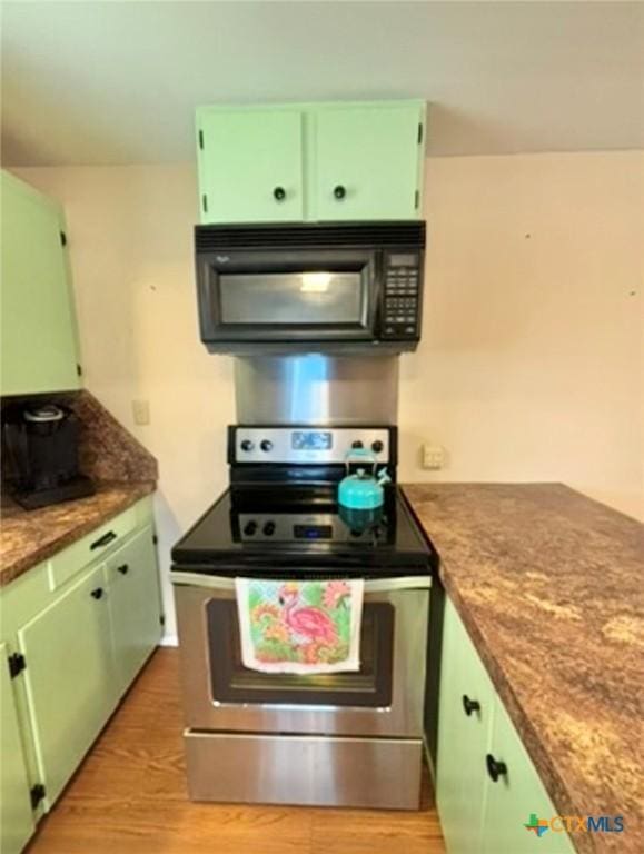 kitchen with electric stove, stone counters, and green cabinets