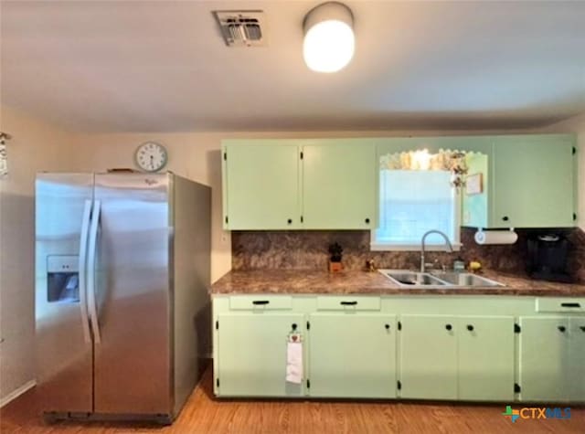 kitchen featuring sink, backsplash, light hardwood / wood-style floors, green cabinetry, and stainless steel refrigerator with ice dispenser