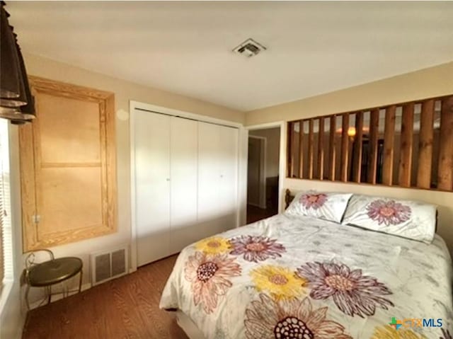 bedroom with dark wood-type flooring and a closet