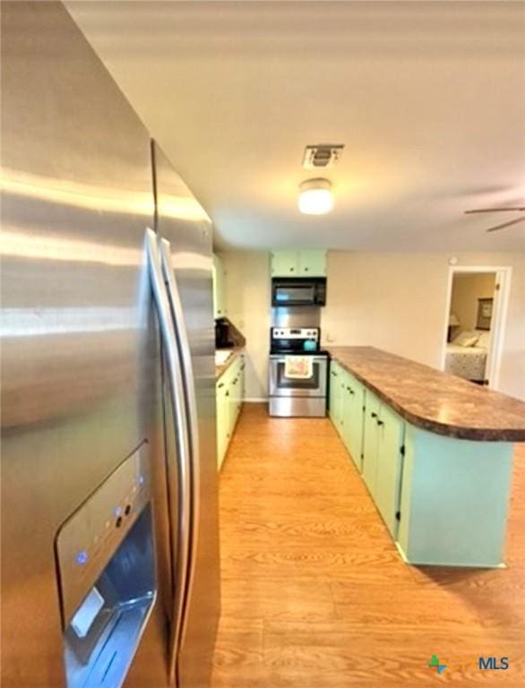 kitchen with green cabinetry, light hardwood / wood-style flooring, kitchen peninsula, ceiling fan, and stainless steel appliances