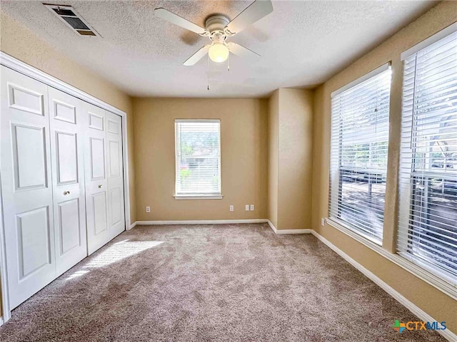 unfurnished bedroom with light colored carpet, multiple windows, and ceiling fan