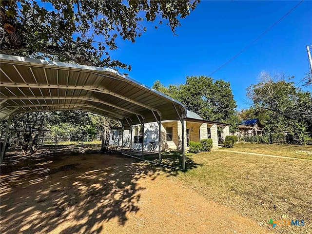 view of parking / parking lot featuring a lawn and a carport