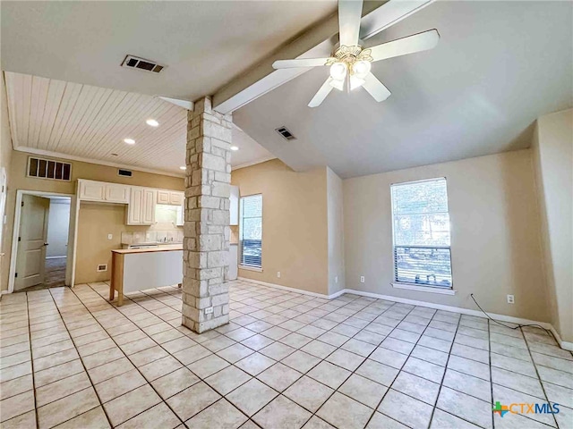 interior space featuring light tile patterned flooring, ceiling fan, vaulted ceiling with beams, decorative columns, and white cabinets