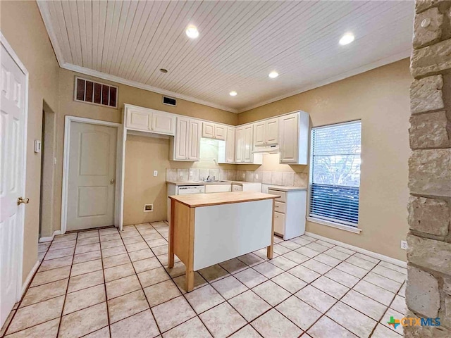 kitchen with white cabinets, ornamental molding, light tile patterned floors, and a kitchen island