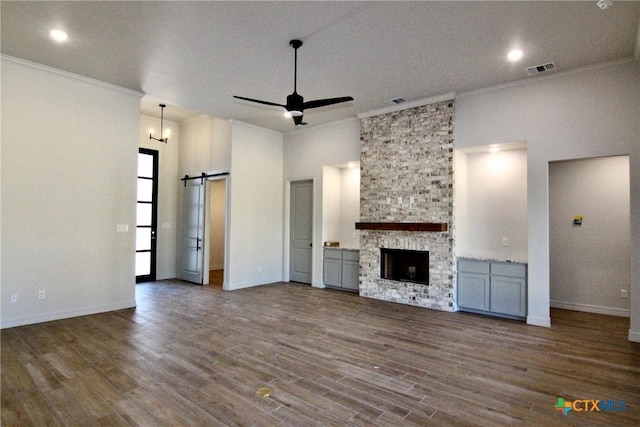 5715 Sparrow Ct, Temple, TX 76502 - unfurnished living room featuring a barn door, ornamental molding, ceiling fan, dark wood finished floors, and baseboards