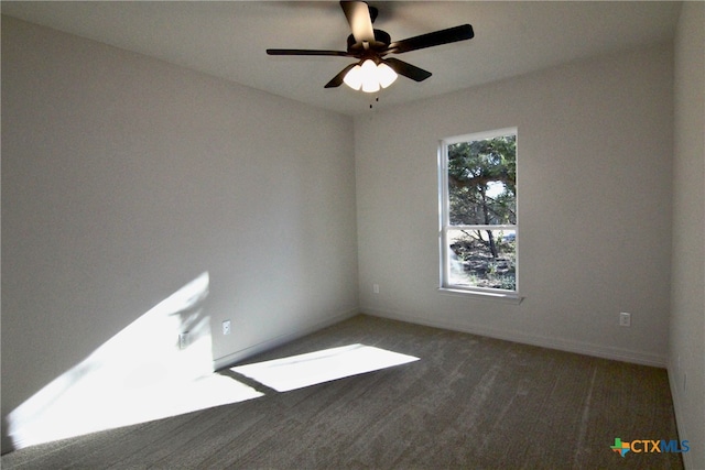 spare room featuring dark colored carpet and ceiling fan