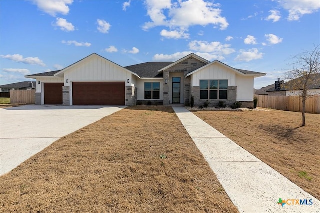 view of front facade with driveway, brick siding, an attached garage, and fence