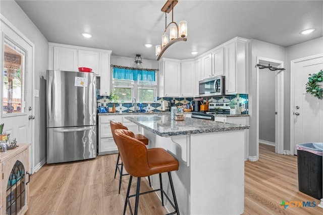 kitchen featuring white cabinetry, stone counters, stainless steel appliances, and a breakfast bar area