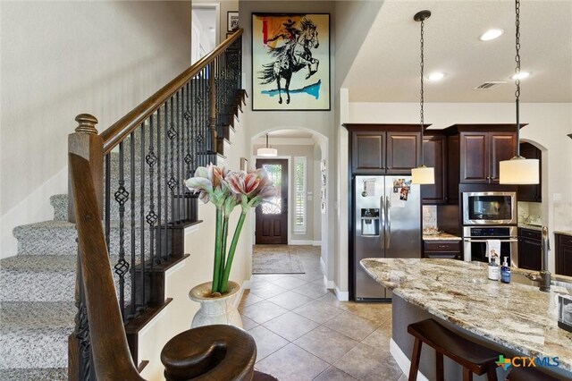 1919 Los Santos Dr, San Marcos, TX 78666 - interior space featuring dark brown cabinetry, light tile patterned floors, visible vents, appliances with stainless steel finishes, and arched walkways