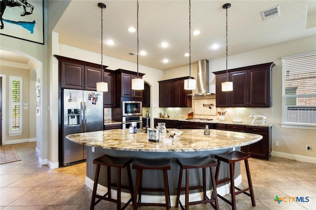 1919 Los Santos Dr, San Marcos, TX 78666 - kitchen with arched walkways, wall chimney range hood, visible vents, and stainless steel appliances