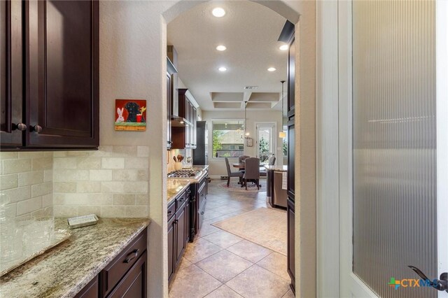 1919 Los Santos Dr, San Marcos, TX 78666 - kitchen with recessed lighting, backsplash, dark brown cabinets, light stone countertops, and arched walkways