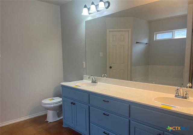 bathroom featuring a sink, toilet, double vanity, and baseboards
