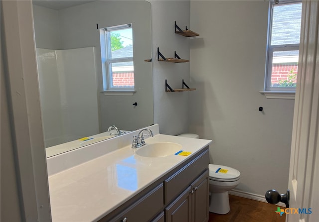 full bath featuring toilet, vanity, baseboards, and walk in shower