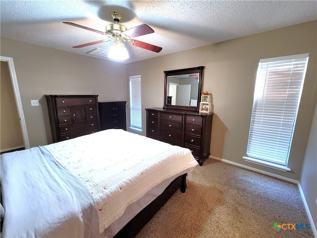 bedroom with ceiling fan, light colored carpet, and a textured ceiling