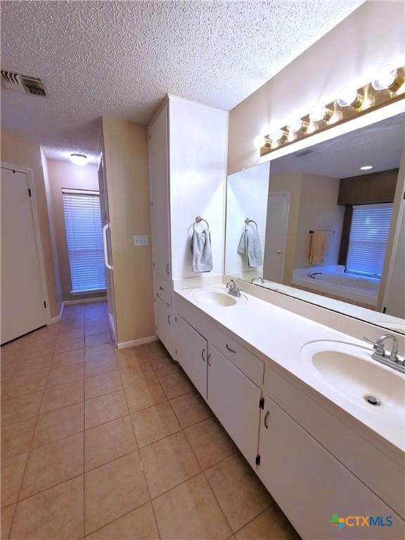 bathroom with vanity, a textured ceiling, tile patterned floors, and a washtub