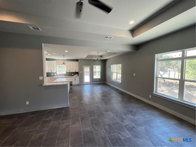 unfurnished living room featuring a raised ceiling and a notable chandelier