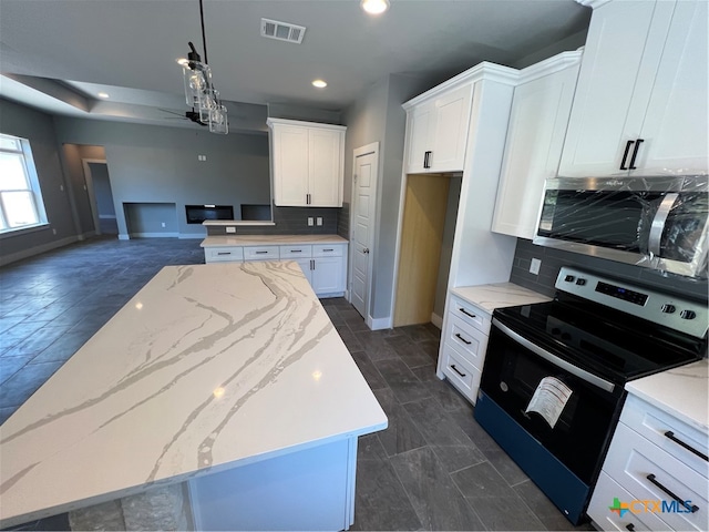 kitchen with white cabinetry, light stone countertops, hanging light fixtures, black electric range, and a kitchen island