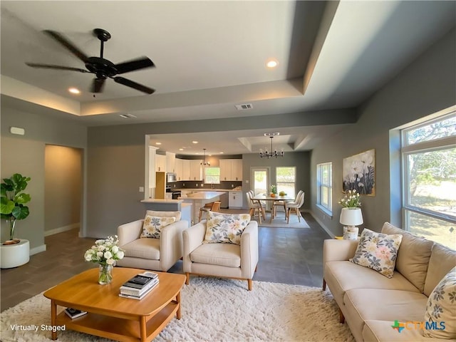 living room with a tray ceiling, visible vents, baseboards, and recessed lighting