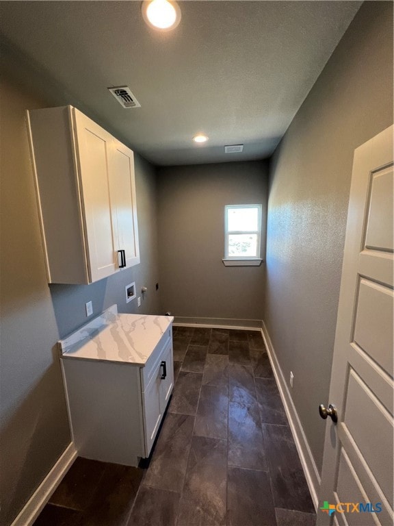 clothes washing area featuring hookup for a washing machine and cabinets