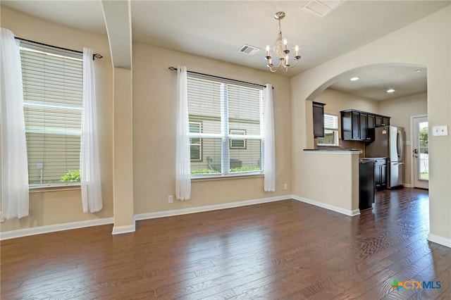 unfurnished living room with dark hardwood / wood-style floors, a healthy amount of sunlight, and a chandelier