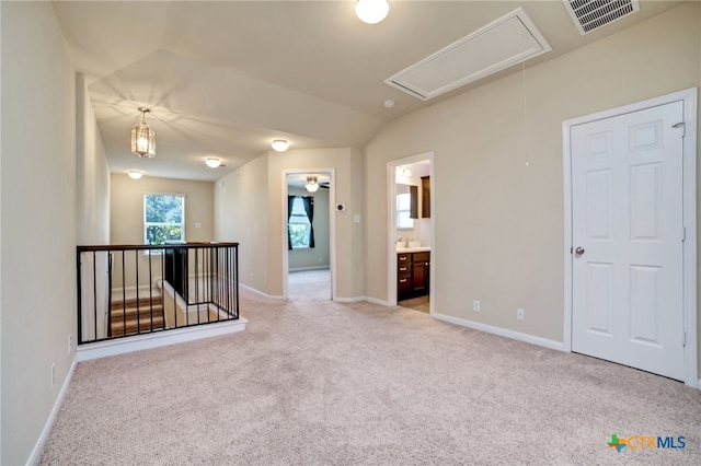 spare room featuring light carpet and vaulted ceiling