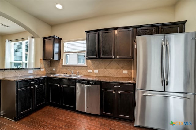 kitchen featuring dark hardwood / wood-style flooring, sink, dark stone countertops, and stainless steel appliances