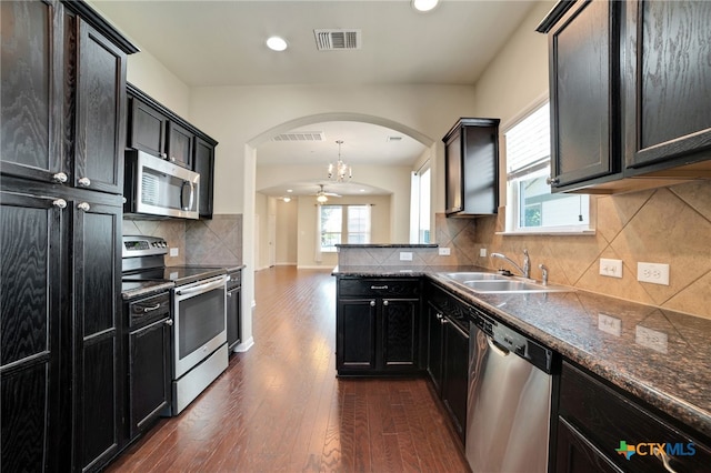 kitchen with sink, appliances with stainless steel finishes, dark hardwood / wood-style floors, hanging light fixtures, and decorative backsplash