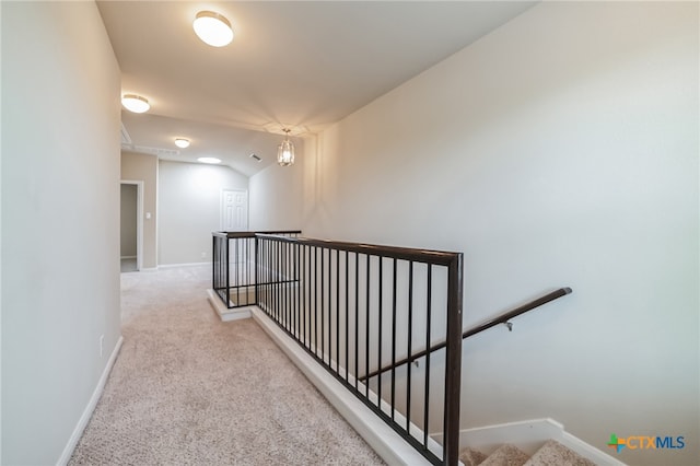 corridor with lofted ceiling and light colored carpet