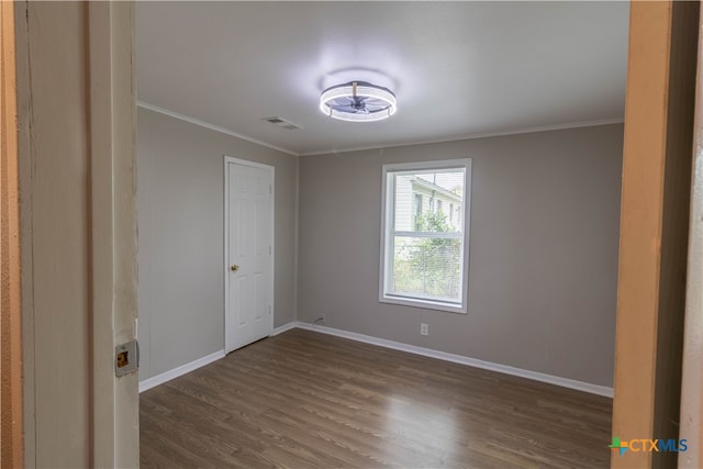 unfurnished room with dark hardwood / wood-style flooring and ornamental molding