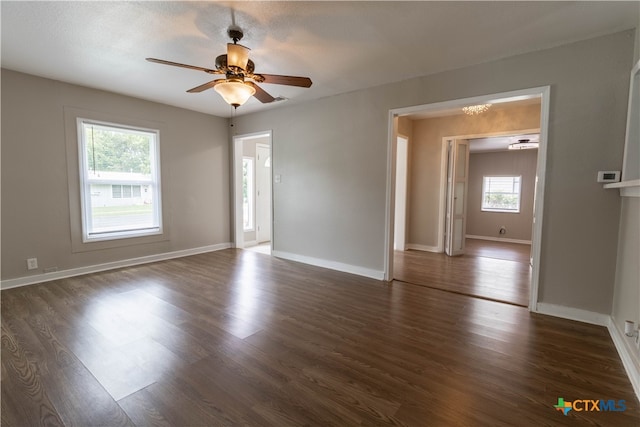 empty room with dark hardwood / wood-style floors, a wealth of natural light, and ceiling fan