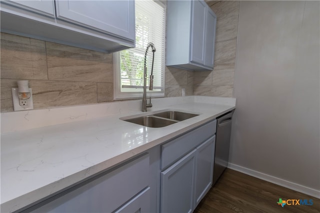 kitchen with light stone countertops, decorative backsplash, stainless steel dishwasher, sink, and dark hardwood / wood-style floors