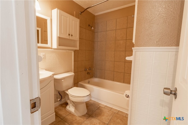 full bathroom featuring vanity, tile patterned flooring, tiled shower / bath combo, toilet, and a textured ceiling