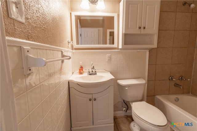 full bathroom featuring washtub / shower combination, vanity, tile walls, and toilet