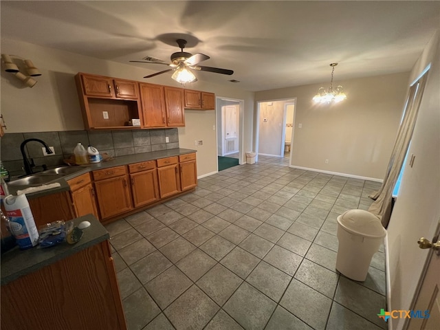 kitchen with sink, ceiling fan with notable chandelier, light tile patterned floors, backsplash, and pendant lighting