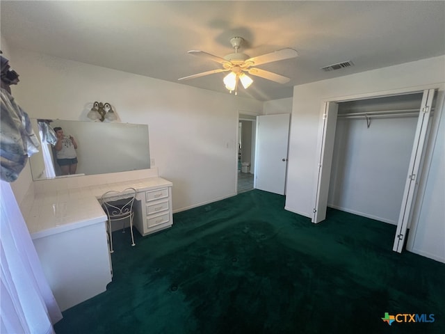 unfurnished bedroom with ceiling fan, dark colored carpet, and a closet