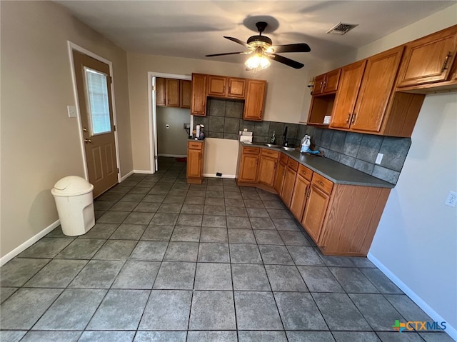 kitchen with ceiling fan, sink, backsplash, and dark tile patterned floors