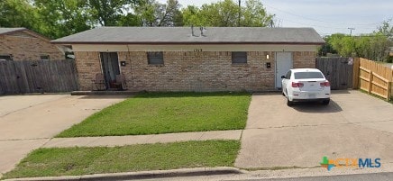 single story home with concrete driveway, brick siding, and fence