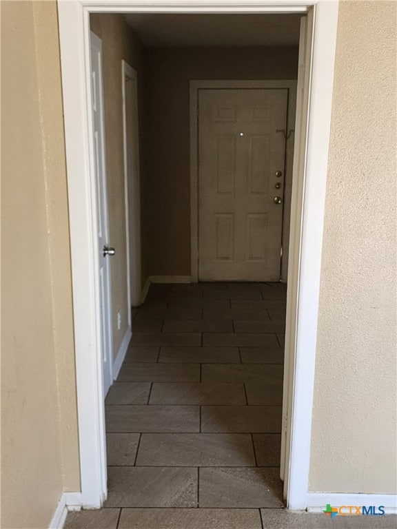 hallway with a textured wall and baseboards