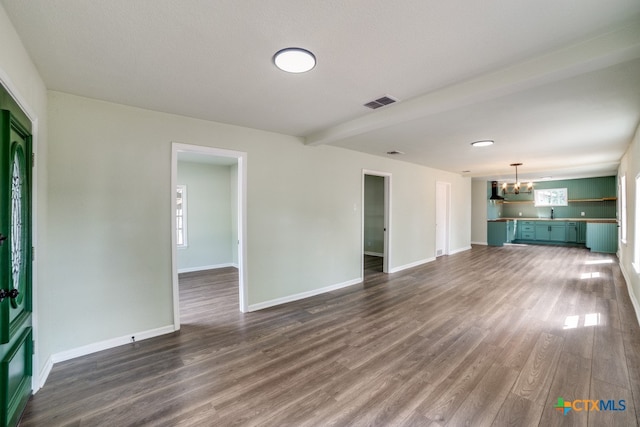 unfurnished living room featuring a textured ceiling, beamed ceiling, dark wood-type flooring, and a healthy amount of sunlight