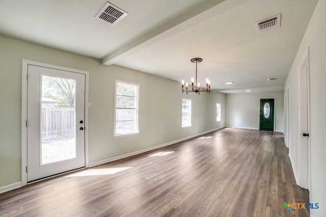 interior space with hardwood / wood-style floors, a textured ceiling, beam ceiling, and an inviting chandelier