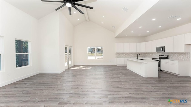 kitchen with white cabinets, high vaulted ceiling, appliances with stainless steel finishes, and an island with sink